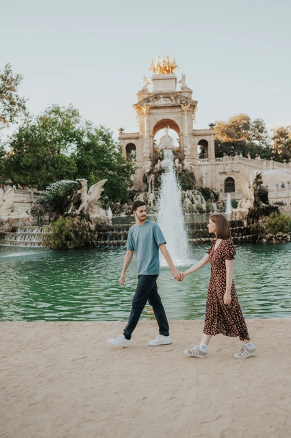 Hand-in-hand portraits by the fountain | Barcelona couple photoshoot The couple holding hands beside the green pool, with the fountain monument in the background during their couple photoshoot in Barcelona.