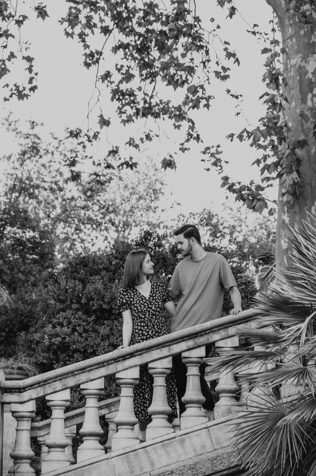 Black-and-white photograph: a closer portrait of the couple leaning towards each other behind the staircase balustrade during their couple photoshoot in Barcelona.