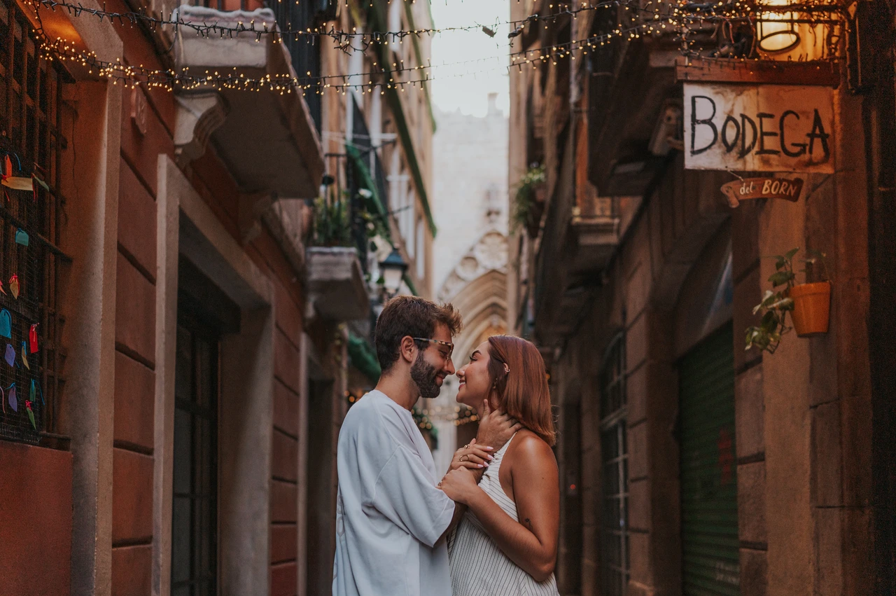 A close portrait in the decorated lane | Barcelona couple photoshoot The couple leaning close together beneath a Bodega del Born sign in a narrow decorated lane during their couple photoshoot in Barcelona.