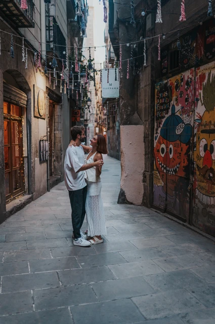 Together among the lane’s colourful details | Barcelona couple photoshoot The couple holding each other in a narrow lane beside a colourful mural and hanging decorations during their couple photoshoot in Barcelona.