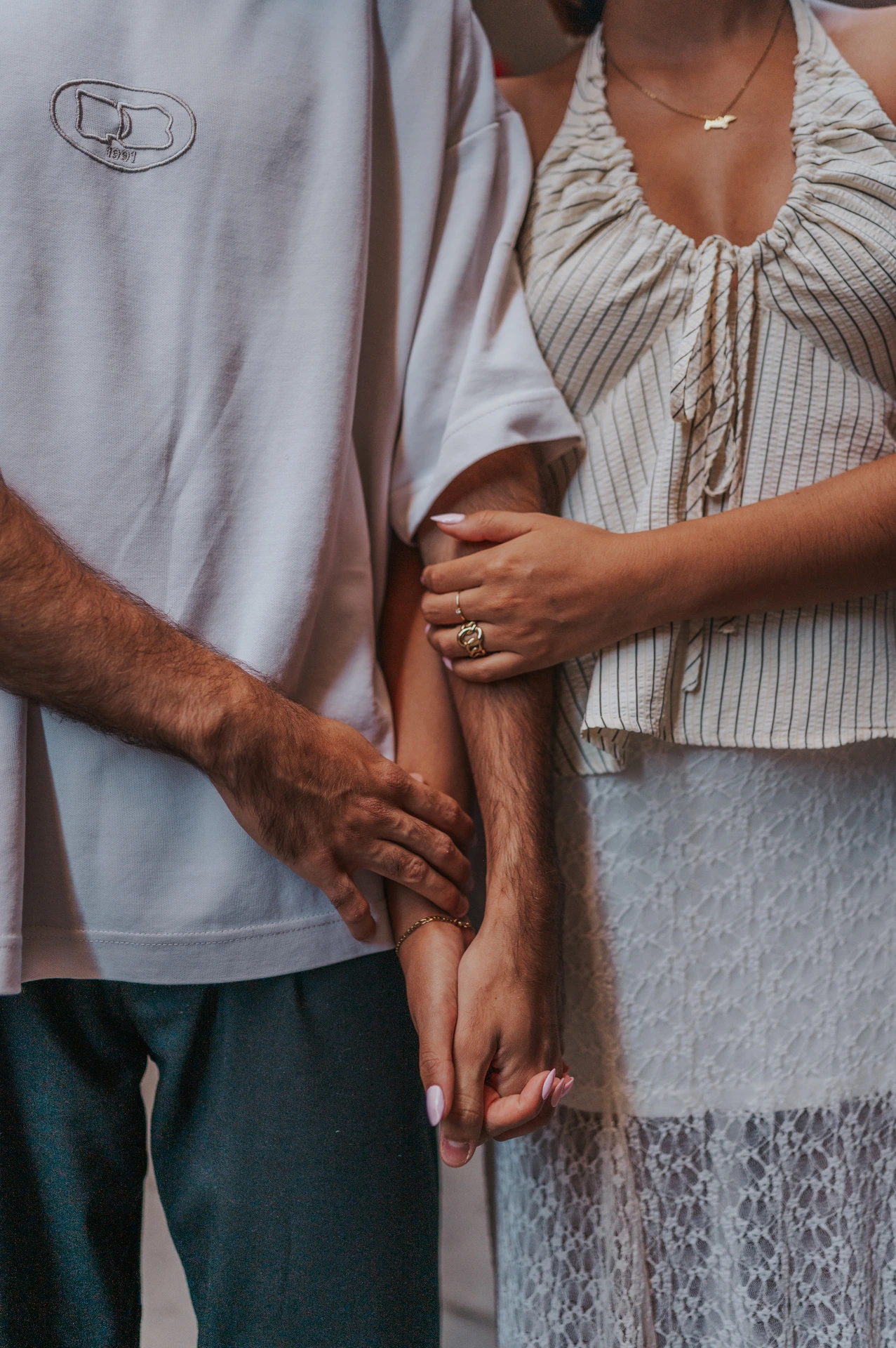 A close detail of the couple holding hands, with the woman’s other hand resting on her partner’s forearm during their couple photoshoot in Barcelona.