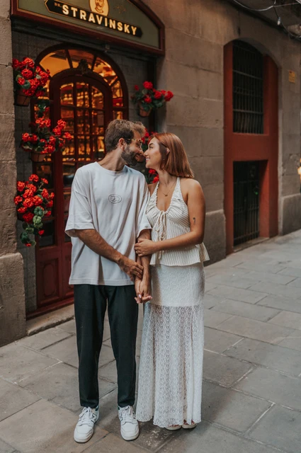 A kiss beside the flower-framed doorway | Barcelona couple photoshoot The couple kissing beside a doorway framed by clusters of red flowers during their couple photoshoot in Barcelona.