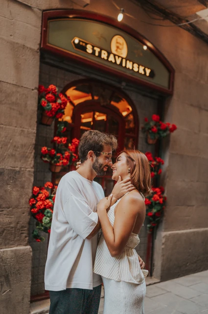 A close view of the couple leaning together beside a doorway decorated with red flowers during their couple photoshoot in Barcelona.