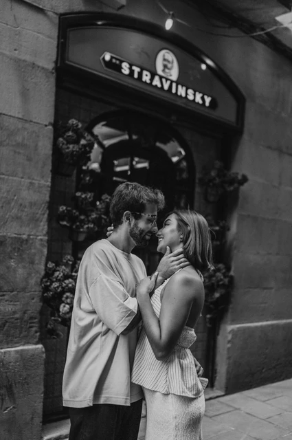 A close portrait beside the arched doorway in black and white | Barcelona couple photoshoot Black-and-white photograph of the couple leaning close together beside an arched doorway surrounded by flowers during their couple photoshoot in Barcelona.