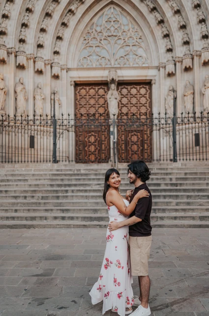 An embrace in front of the cathedral steps | Barcelona couple photoshoot The couple embracing and smiling in front of the stone steps at Barcelona Cathedral during their couple photoshoot in Barcelona.