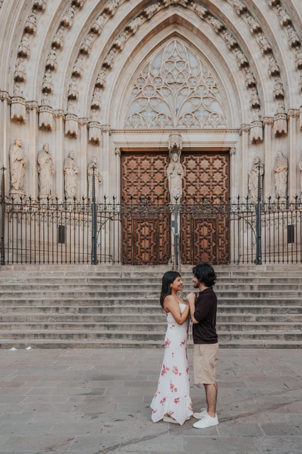 Hand in hand below the cathedral doorway | Barcelona couple photoshoot The couple standing face to face and holding hands below the carved doorway of Barcelona Cathedral during their couple photoshoot in Barcelona.