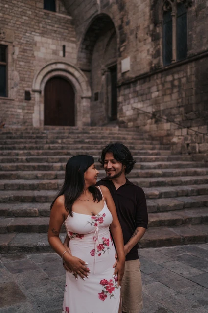 Smiling together in Plaça del Rei | Barcelona couple photoshoot A close portrait of the couple smiling at each other, with the stone steps at Plaça del Rei behind them during their couple photoshoot in Barcelona.