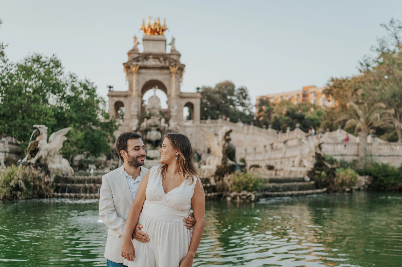 An embrace beside the green fountain pool | Barcelona engagement photoshoot The man holding his partner close beside the fountain pool as they look towards each other during their engagement photoshoot in Barcelona.