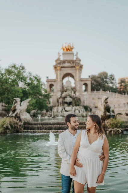 An embrace beside the green fountain pool | Barcelona engagement photoshoot The man holding his partner close beside the fountain pool as they look towards each other during their engagement photoshoot in Barcelona.