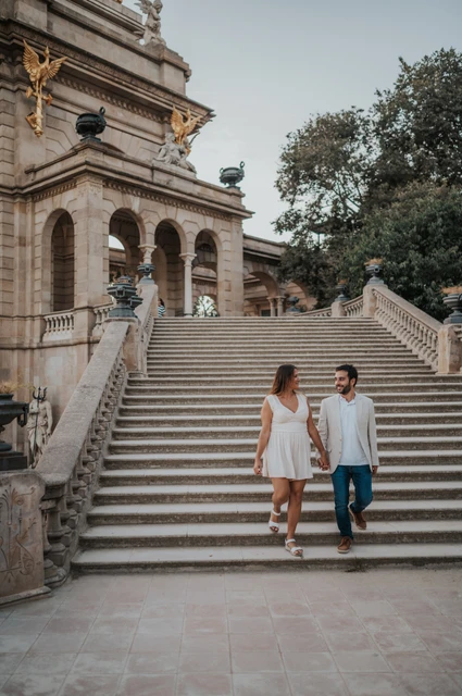 A walk down the fountain staircase | Barcelona engagement photoshoot The couple walking down the broad stone staircase beside the fountain monument during their engagement photoshoot in Barcelona.