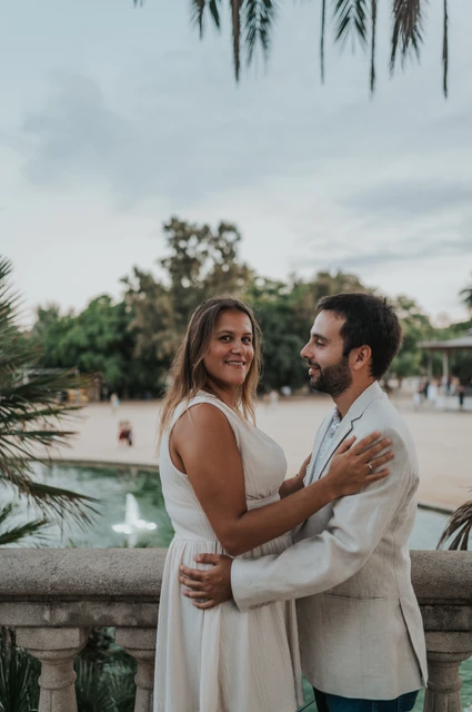 An embrace beside the palm-lined terrace | Barcelona engagement photoshoot The couple holding each other beside the terrace balustrade with palms in the background during their engagement photoshoot in Barcelona.