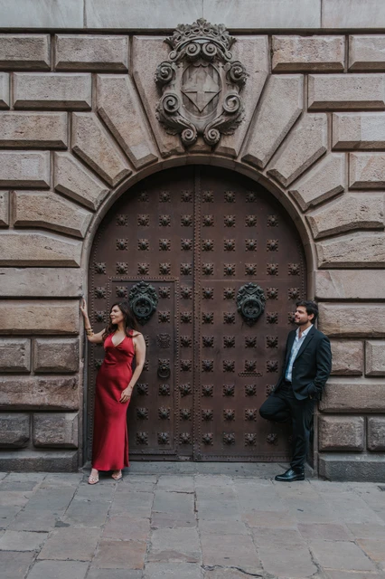 Portraits beside an arched wooden door | Barcelona engagement photoshoot The couple standing on opposite sides of a large studded wooden door in an arched stone entrance in the Gothic Quarter during their engagement photoshoot in Barcelona.