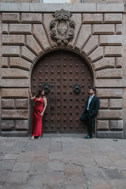 Portraits beside an arched wooden door | Barcelona engagement photoshoot The couple standing on opposite sides of a large studded wooden door in an arched stone entrance in the Gothic Quarter during their engagement photoshoot in Barcelona.