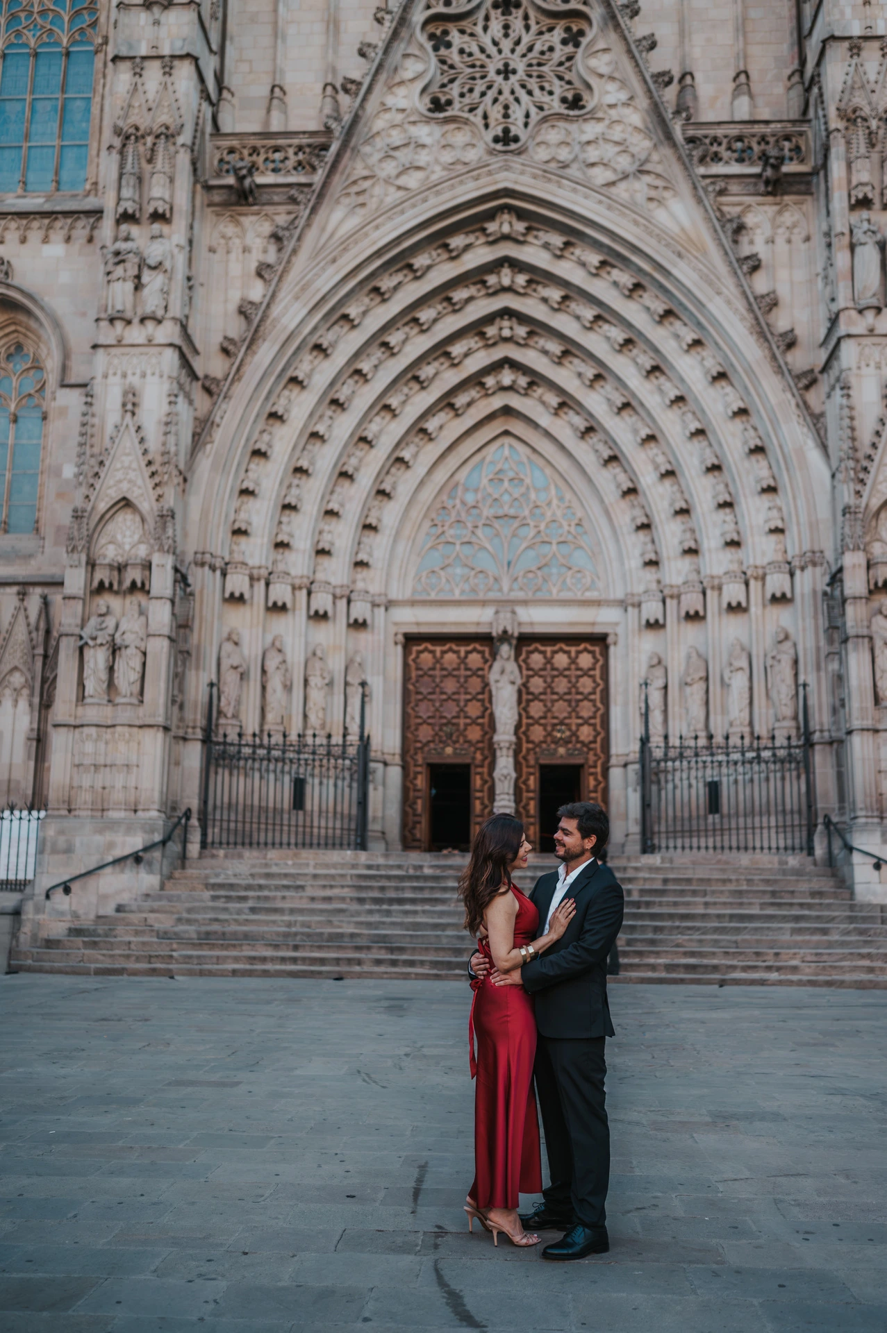 The couple standing close together in front of Barcelona Cathedral’s carved Gothic entrance during their engagement photoshoot in Barcelona.