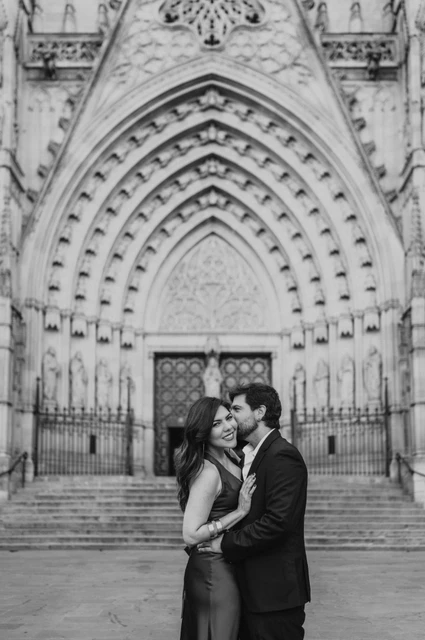 Engagement portraits in front of Barcelona Cathedral in black and white | Barcelona engagement photoshoot Black-and-white photograph: the couple standing close together in front of Barcelona Cathedral’s carved Gothic entrance during their engagement photoshoot in Barcelona.