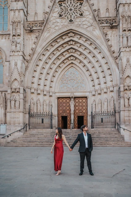 A walk together in front of Barcelona Cathedral | Barcelona engagement photoshoot The couple walking hand in hand and smiling at each other in front of Barcelona Cathedral during their engagement photoshoot in Barcelona.