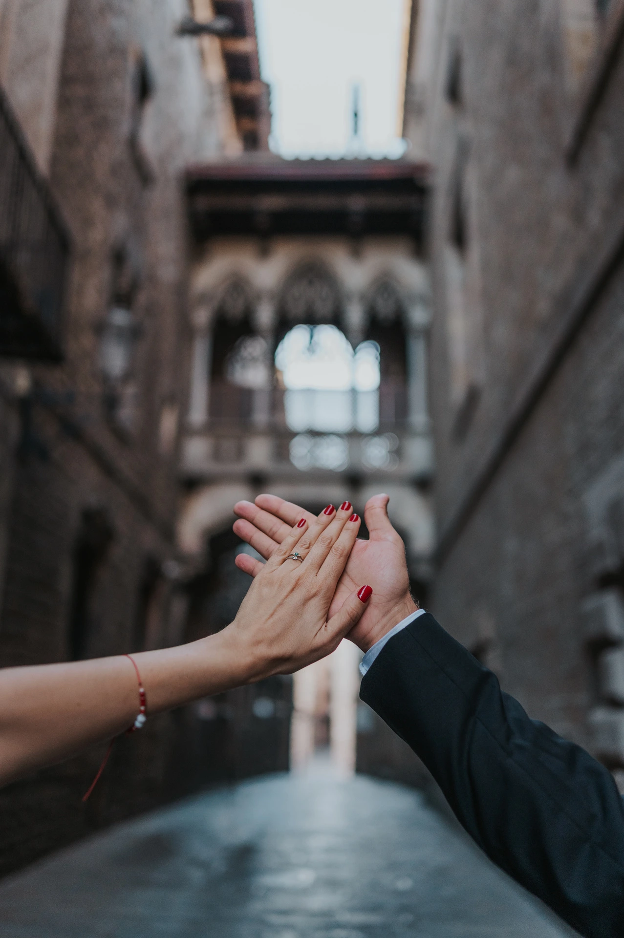A close-up of the couple’s raised hands and engagement ring, with Pont del Bisbe softly blurred behind them during their engagement photoshoot in Barcelona.