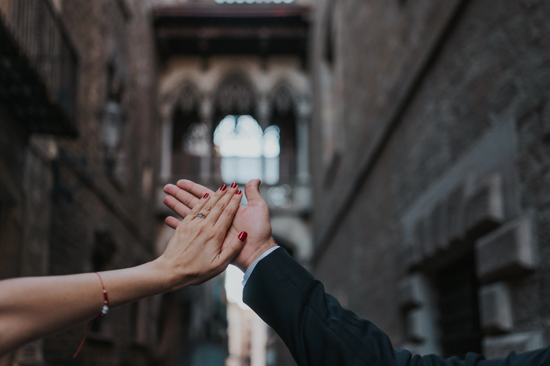 An engagement ring with Pont del Bisbe in the background | Barcelona engagement photoshoot A close-up of the couple’s raised hands and engagement ring, with Pont del Bisbe softly blurred behind them during their engagement photoshoot in Barcelona.