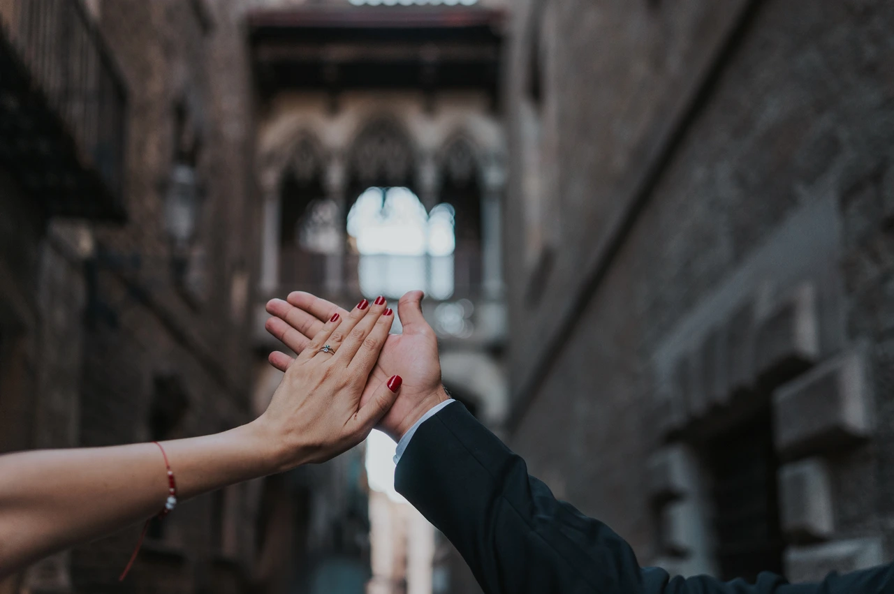 An engagement ring with Pont del Bisbe in the background | Barcelona engagement photoshoot A close-up of the couple’s raised hands and engagement ring, with Pont del Bisbe softly blurred behind them during their engagement photoshoot in Barcelona.
