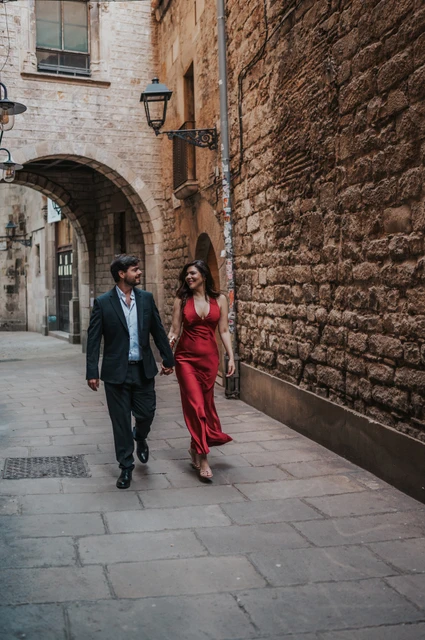 A walk through an arched Gothic Quarter lane | Barcelona engagement photoshoot The couple walking together through a stone lane beneath an arch in the Gothic Quarter during their engagement photoshoot in Barcelona.