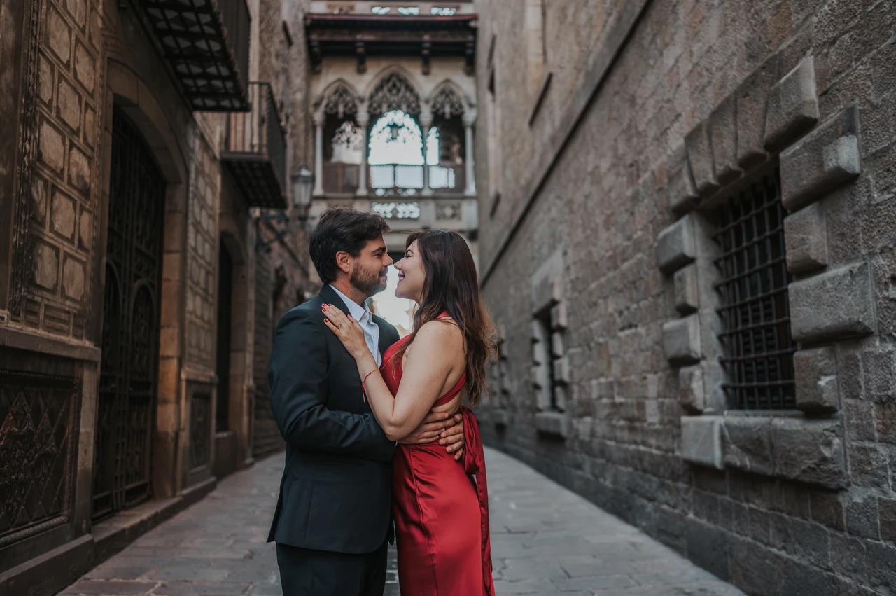 Close together beneath Pont del Bisbe | Barcelona engagement photoshoot The couple standing close together beneath Pont del Bisbe, framed by the Gothic Quarter’s old stone buildings during their engagement photoshoot in Barcelona.