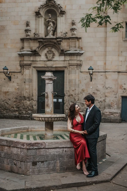 A portrait beside the fountain in Plaça de Sant Felip Neri | Barcelona engagement photoshoot The couple beside the stone fountain in Plaça de Sant Felip Neri, with the church façade behind them during their engagement photoshoot in Barcelona.