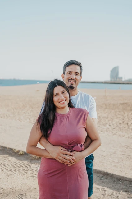 A portrait for the parents with the W Hotel behind them | Barcelona family photoshoot The parents embracing on the sand, with the sea and W Hotel behind them during their family photoshoot in Barcelona.
