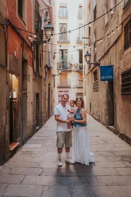 Together in an El Born lane | Barcelona family photoshoot The parents holding their toddler together in a narrow El Born lane lined with balconies during their family photoshoot in Barcelona.