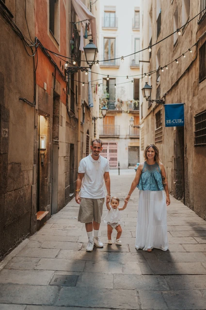 A hand-in-hand family walk in El Born | Barcelona family photoshoot The toddler walking between the parents and holding their hands on an El Born street during their family photoshoot in Barcelona.