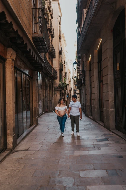 Walking together through the old streets | Barcelona maternity photoshoot The couple walking together along a narrow street lined with old buildings during their maternity photoshoot in Barcelona.