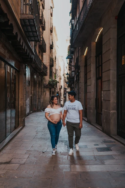 Walking together through the old streets | Barcelona maternity photoshoot The couple walking together along a narrow street lined with old buildings during their maternity photoshoot in Barcelona.