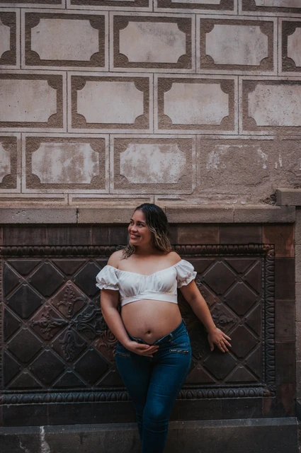 A maternity portrait beside the patterned wall | Barcelona maternity photoshoot The mother-to-be standing beside a patterned wall with her hand resting on her bump during their maternity photoshoot in Barcelona.