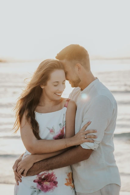 A close-up portrait shows a couple embracing on Dubai beach in warm golden light during a romantic photoshoot.