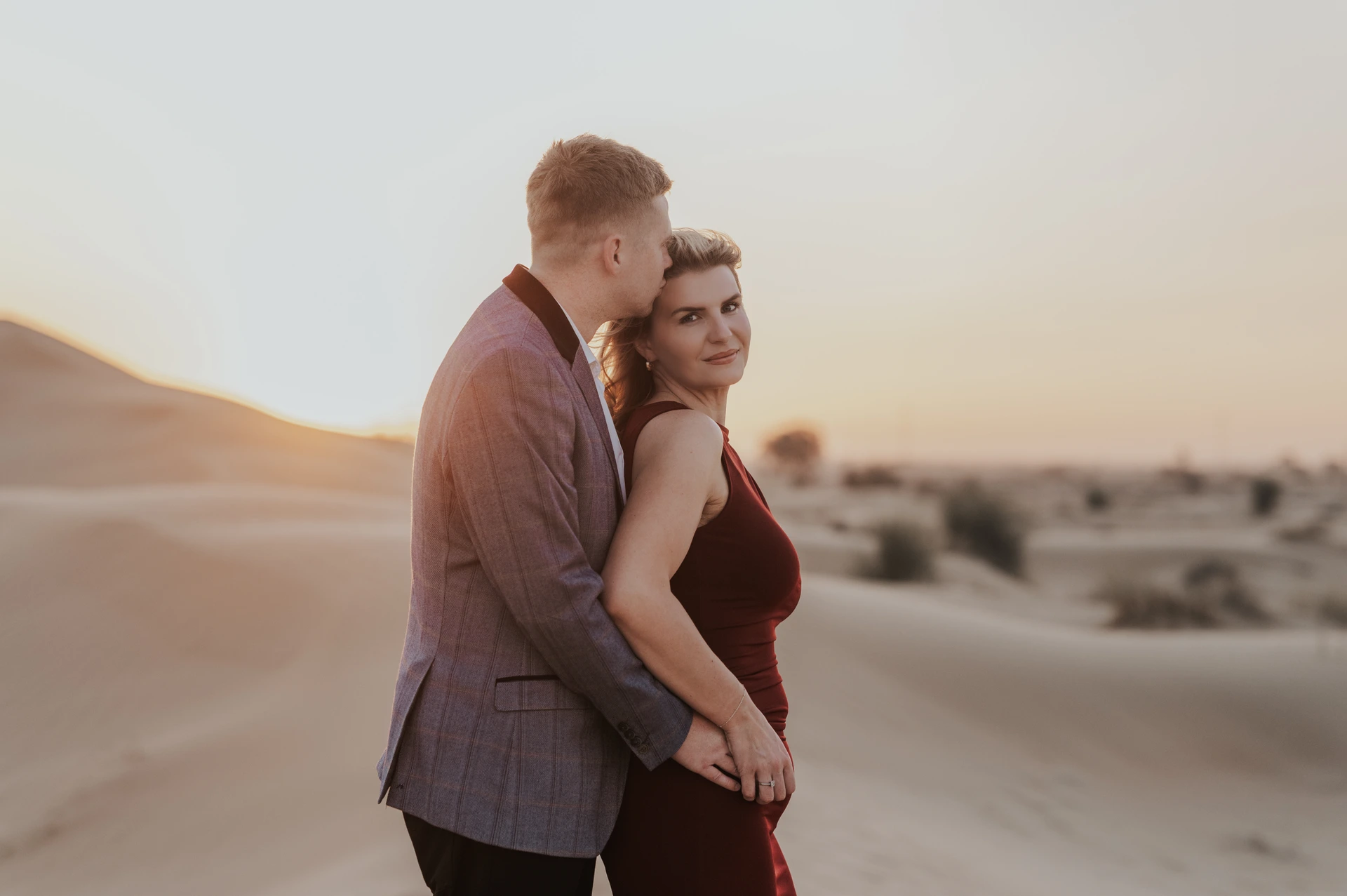 A close portrait of a couple on Dubai sand dunes during golden hour with soft backlight.
