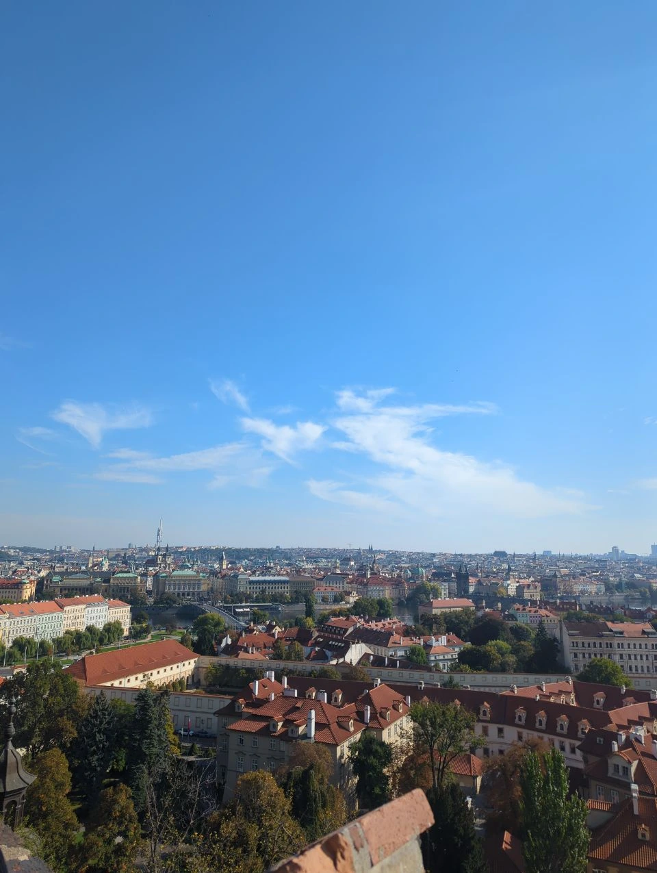 Prague rooftops, bridges and towers spread below the free Na Opyši viewpoint beside Prague Castle.