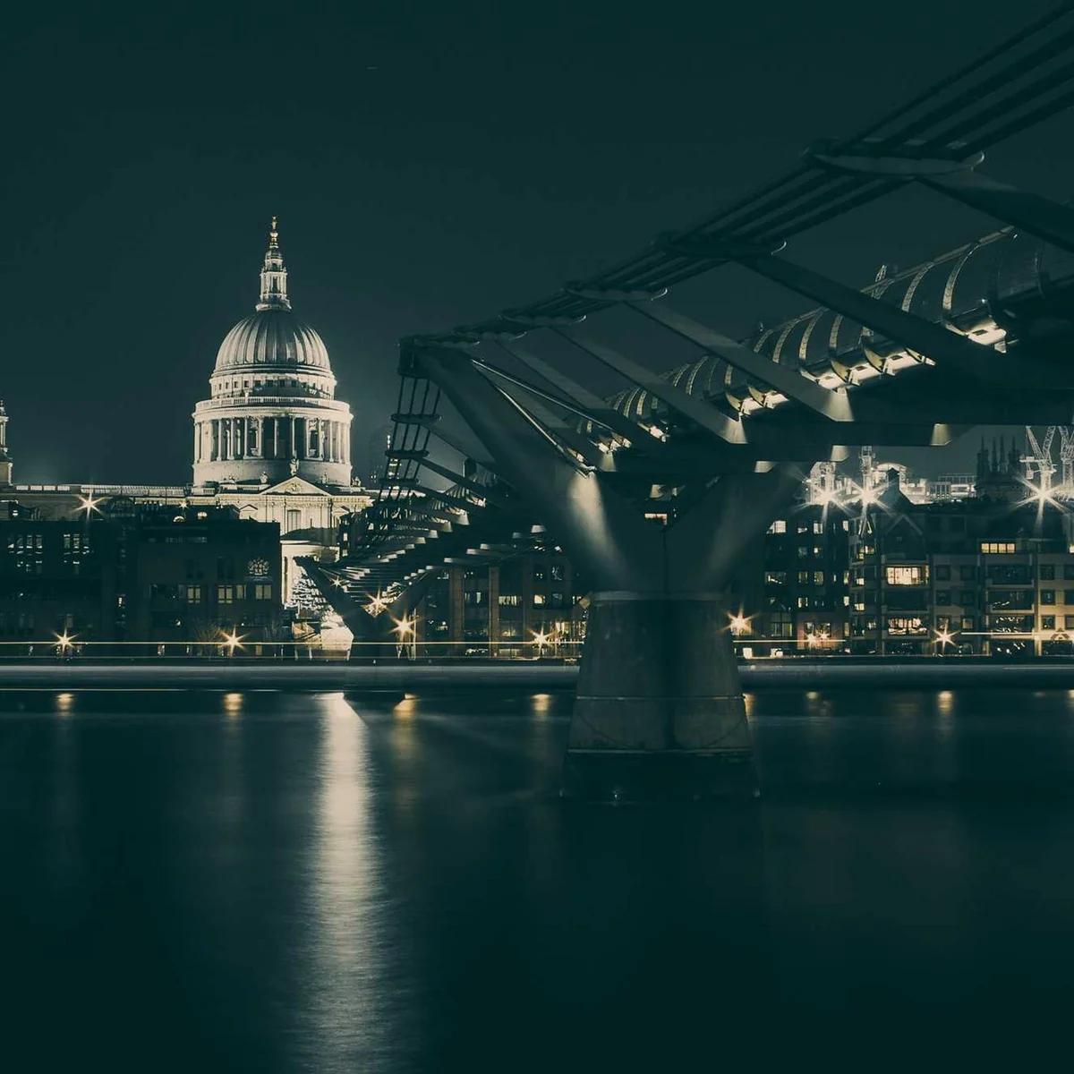 St Paul's Cathedral and Millennium Bridge illuminated at night across River Thames in London