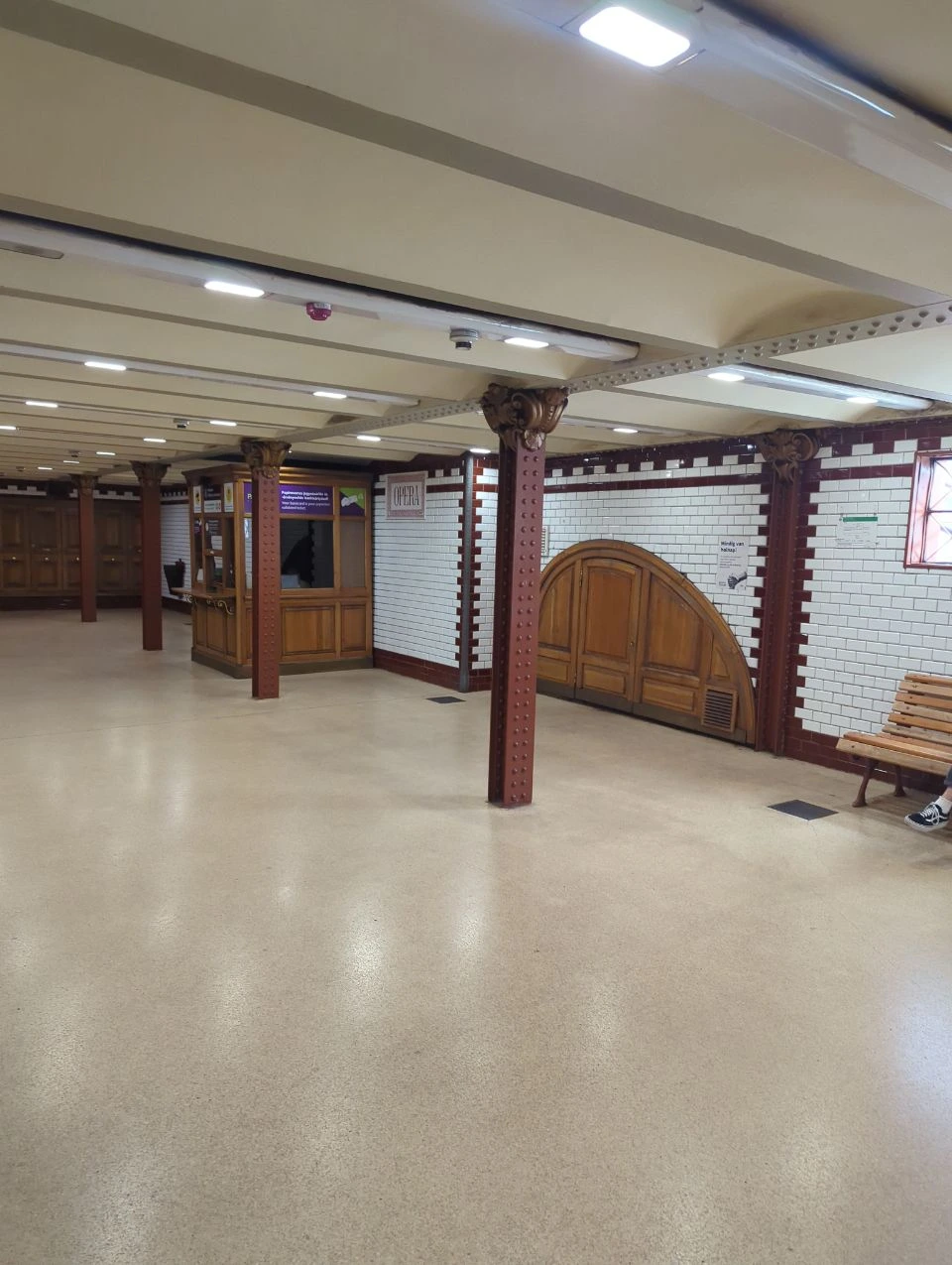 Tiled Opera M1 metro station concourse with iron columns and wooden doors