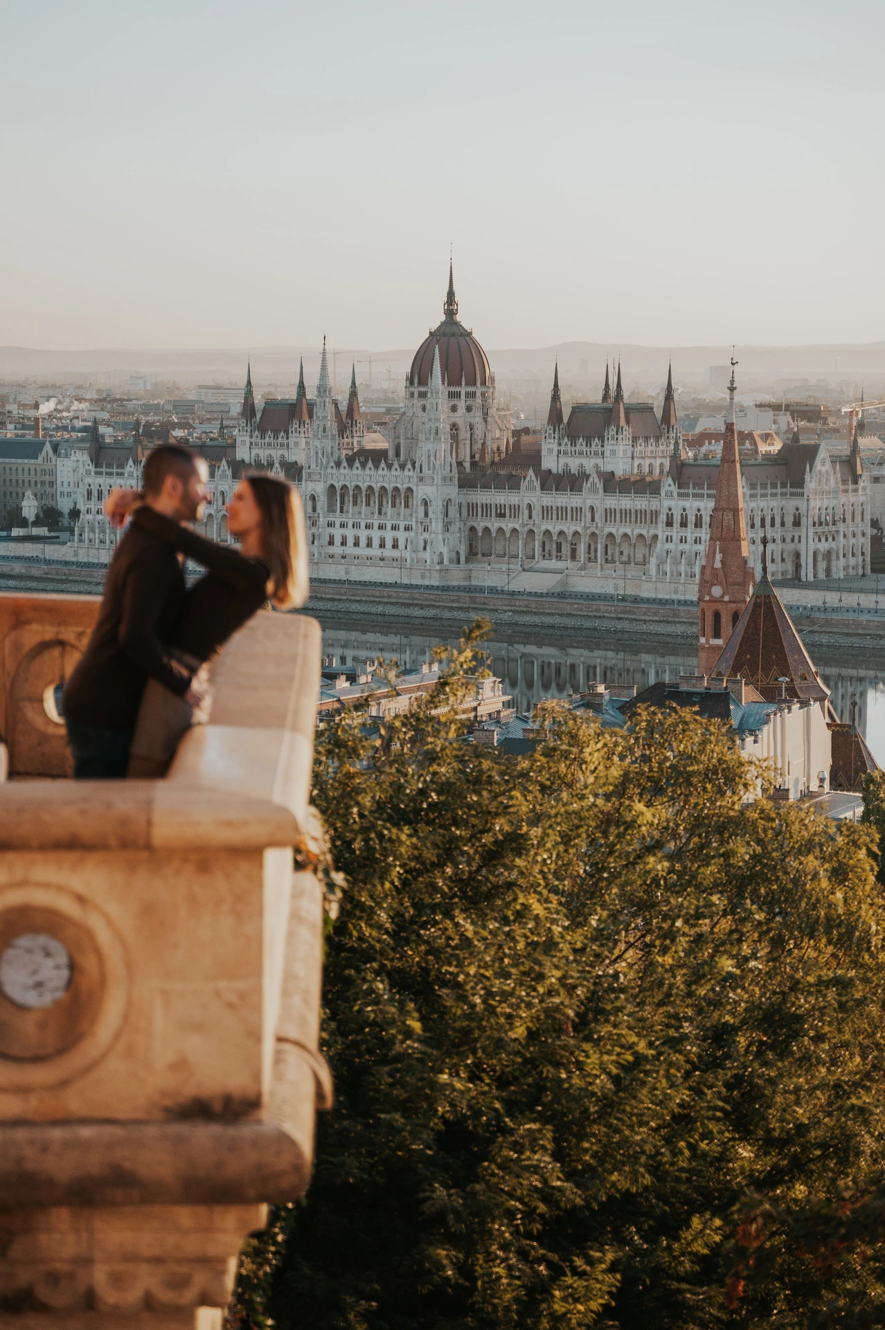 A closer portrait of the couple embracing beside Fisherman’s Bastion’s carved stone balcony with Parliament in the background during their couple photoshoot in Budapest.
