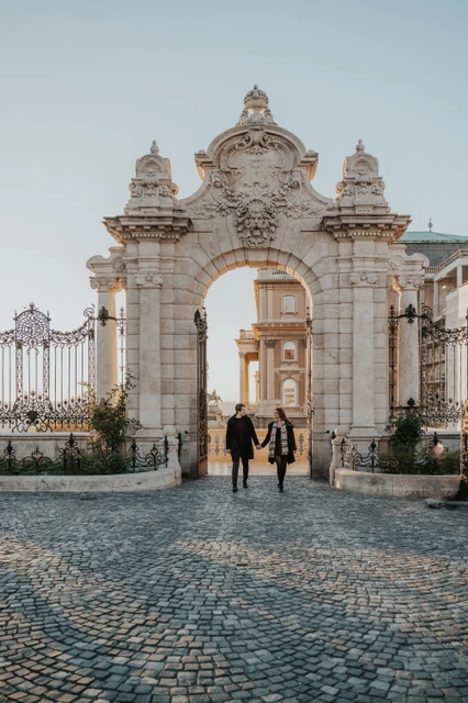 Couple photoshoot in Budapest on the cobbles by the castle gate Couple standing hand in hand on the cobbled approach to the Buda Castle gate during their photoshoot in Budapest