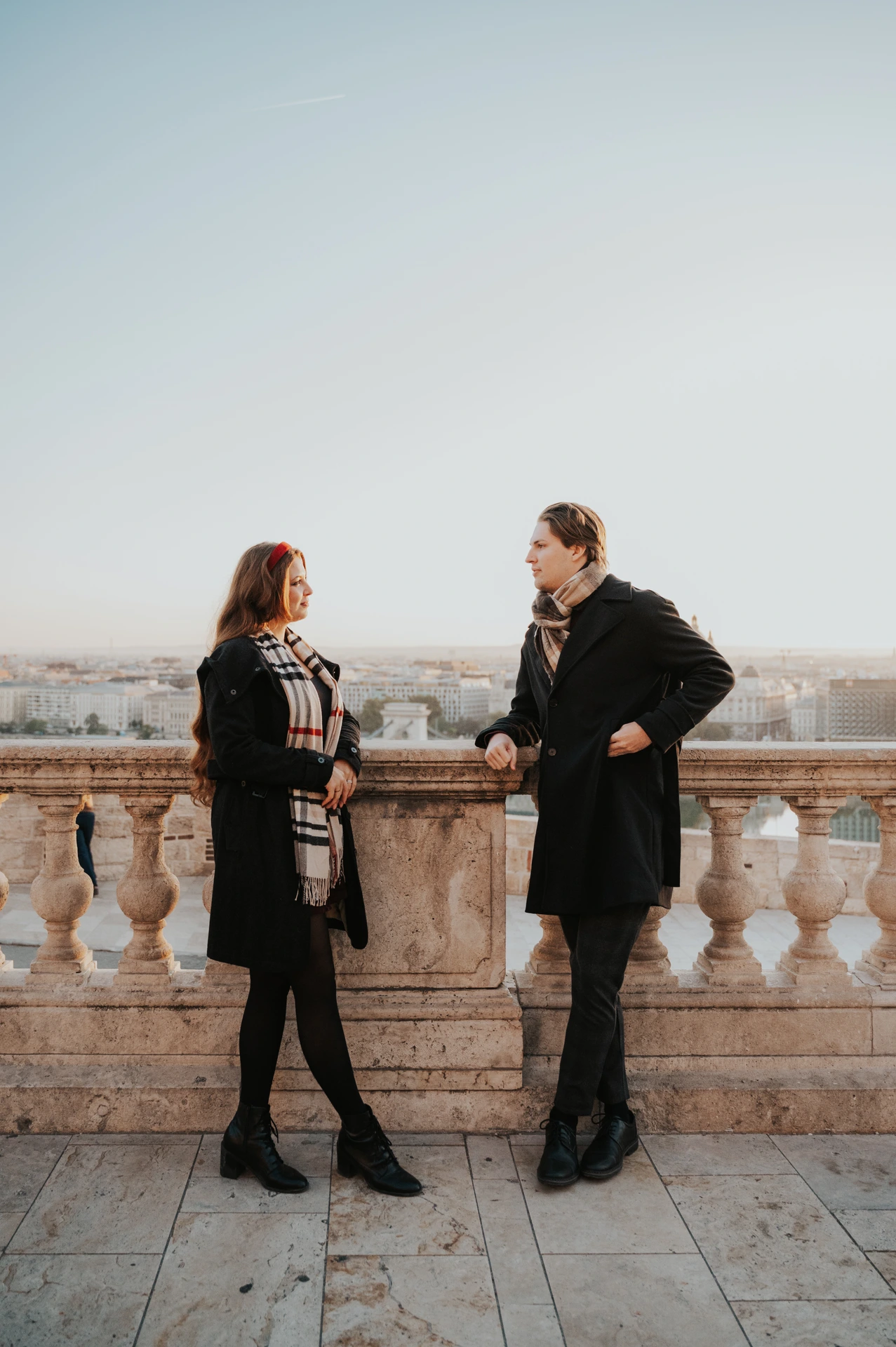 Couple holding hands beside the stone balustrade at Buda Castle during their couple photoshoot in Budapest