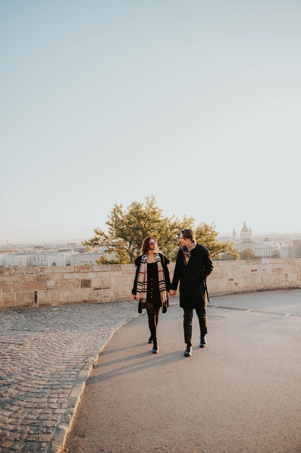 Couple walking hand in hand through the Buda Castle grounds during their morning photoshoot in Budapest