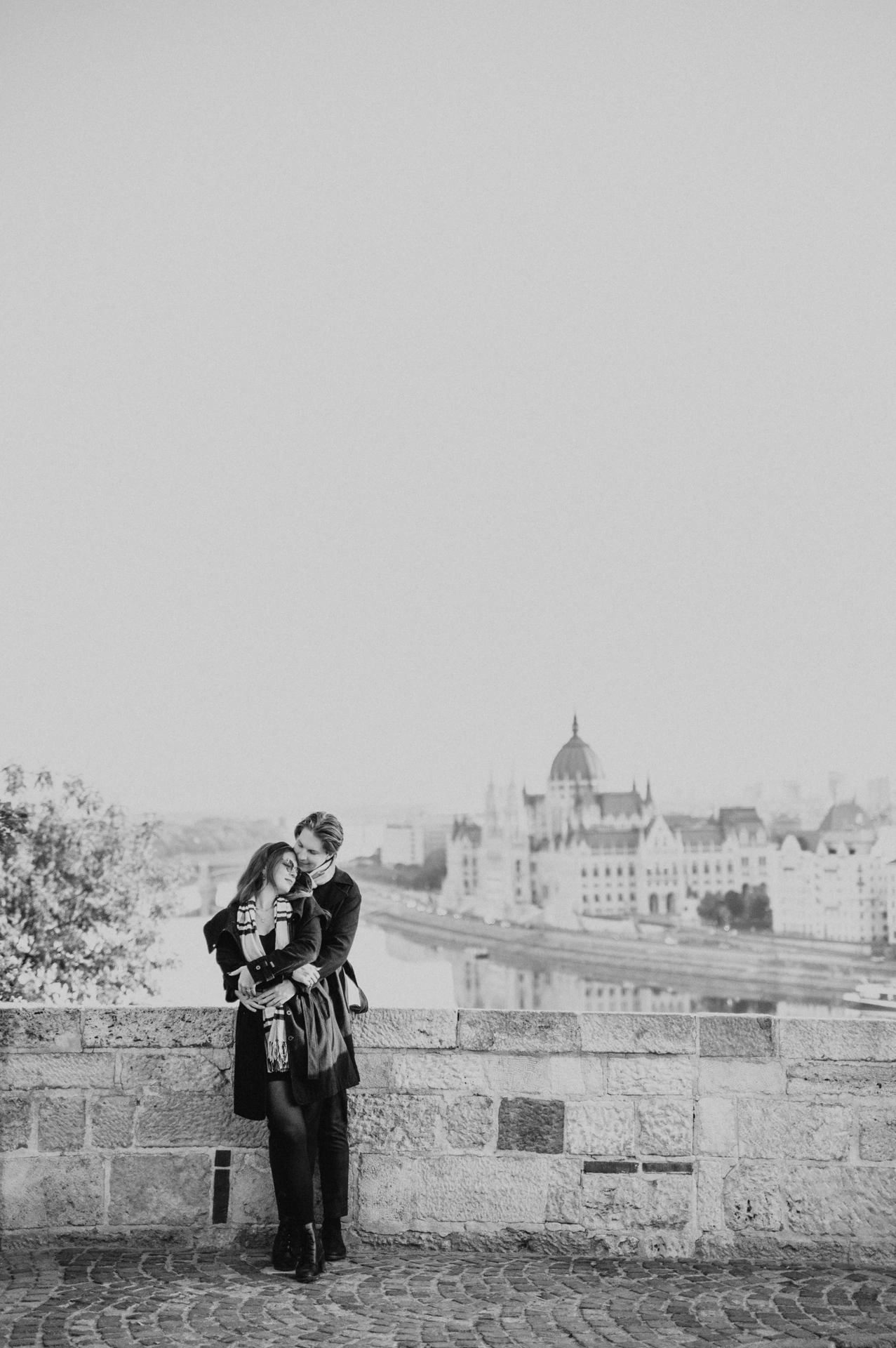Black and white photograph of a couple leaning close at the Buda Castle parapet during their Budapest couple photoshoot