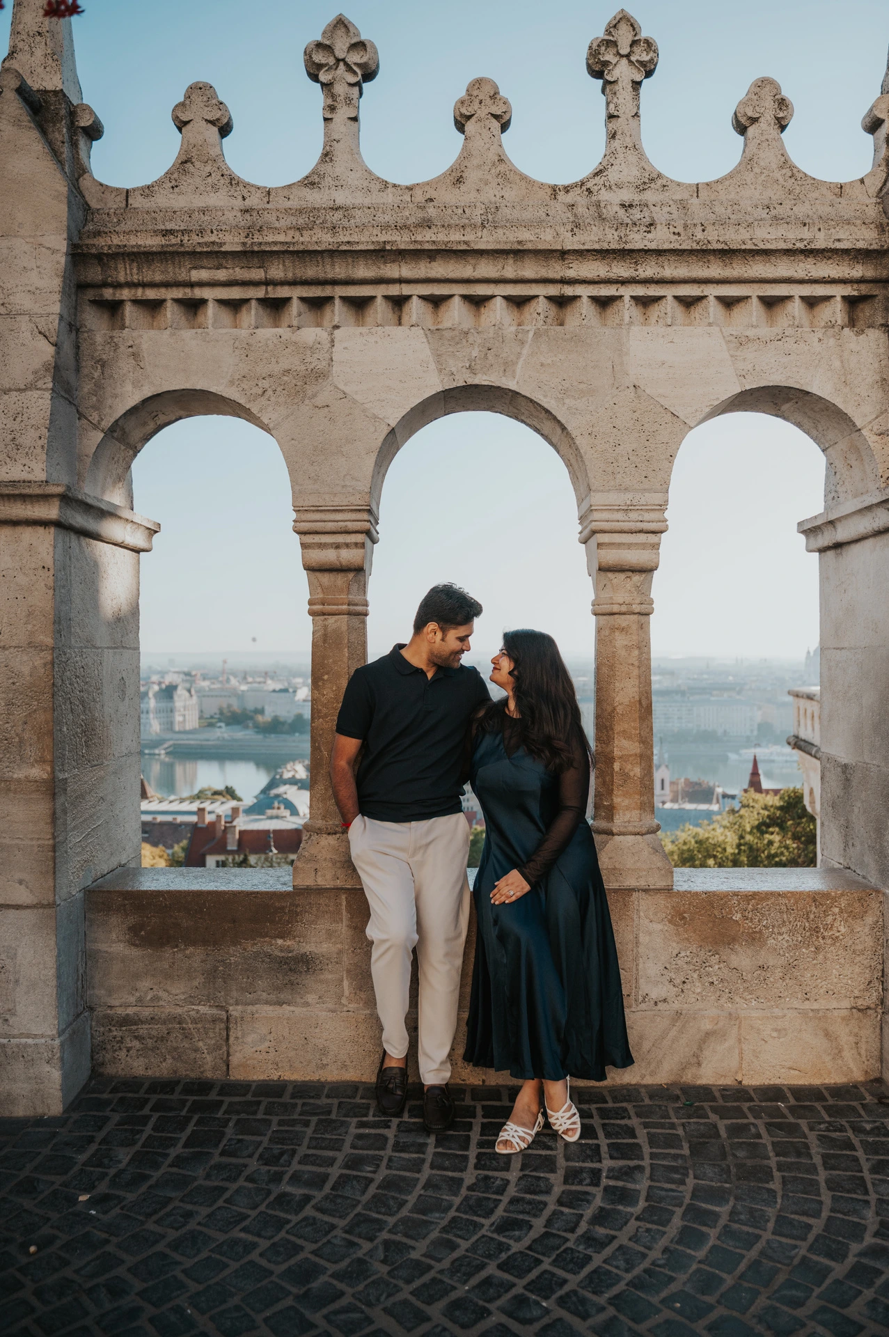 The couple standing together beneath the ornate row of arches at Fisherman’s Bastion during a couple photoshoot in Budapest.