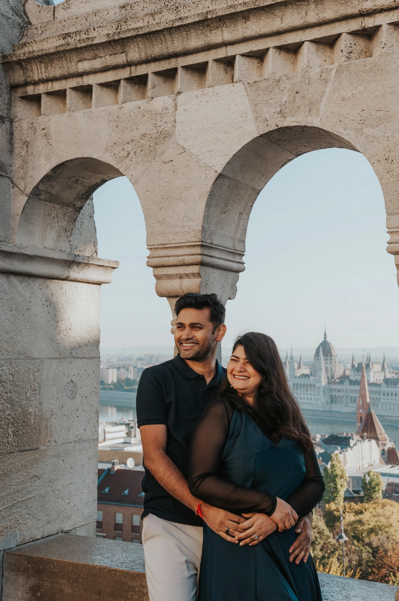 The couple looking to the side together beside a stone arch at Fisherman’s Bastion during a couple photoshoot in Budapest.