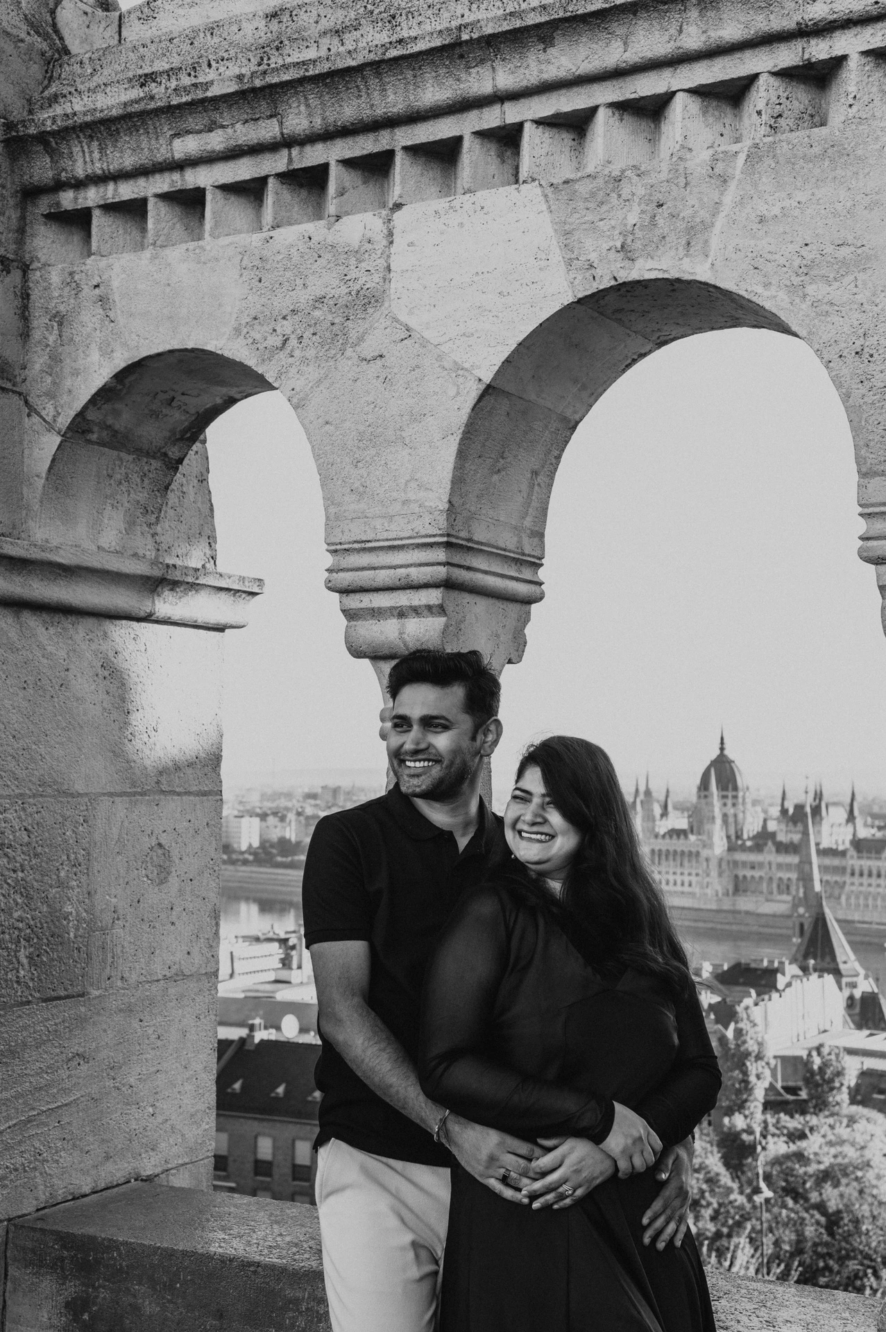 Black-and-white photograph of a closer portrait of the couple looking out beside the stone arcade at Fisherman’s Bastion during a couple photoshoot in Budapest.