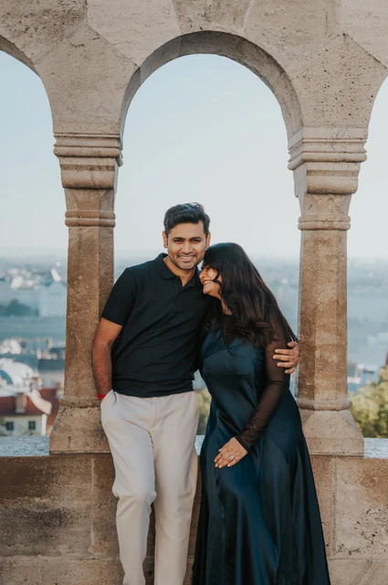 Budapest couple photoshoot: smiles beneath a stone Bastion arch The smiling couple leaning close beneath a stone arch at Fisherman’s Bastion during a couple photoshoot in Budapest.
