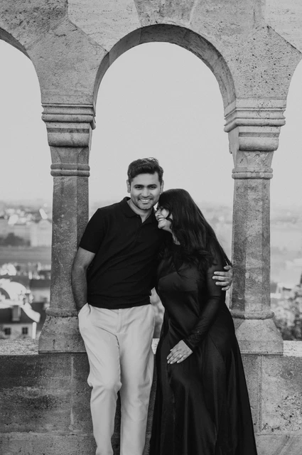 Black-and-white photograph of the smiling couple beneath a rounded arch at Fisherman’s Bastion during a couple photoshoot in Budapest.