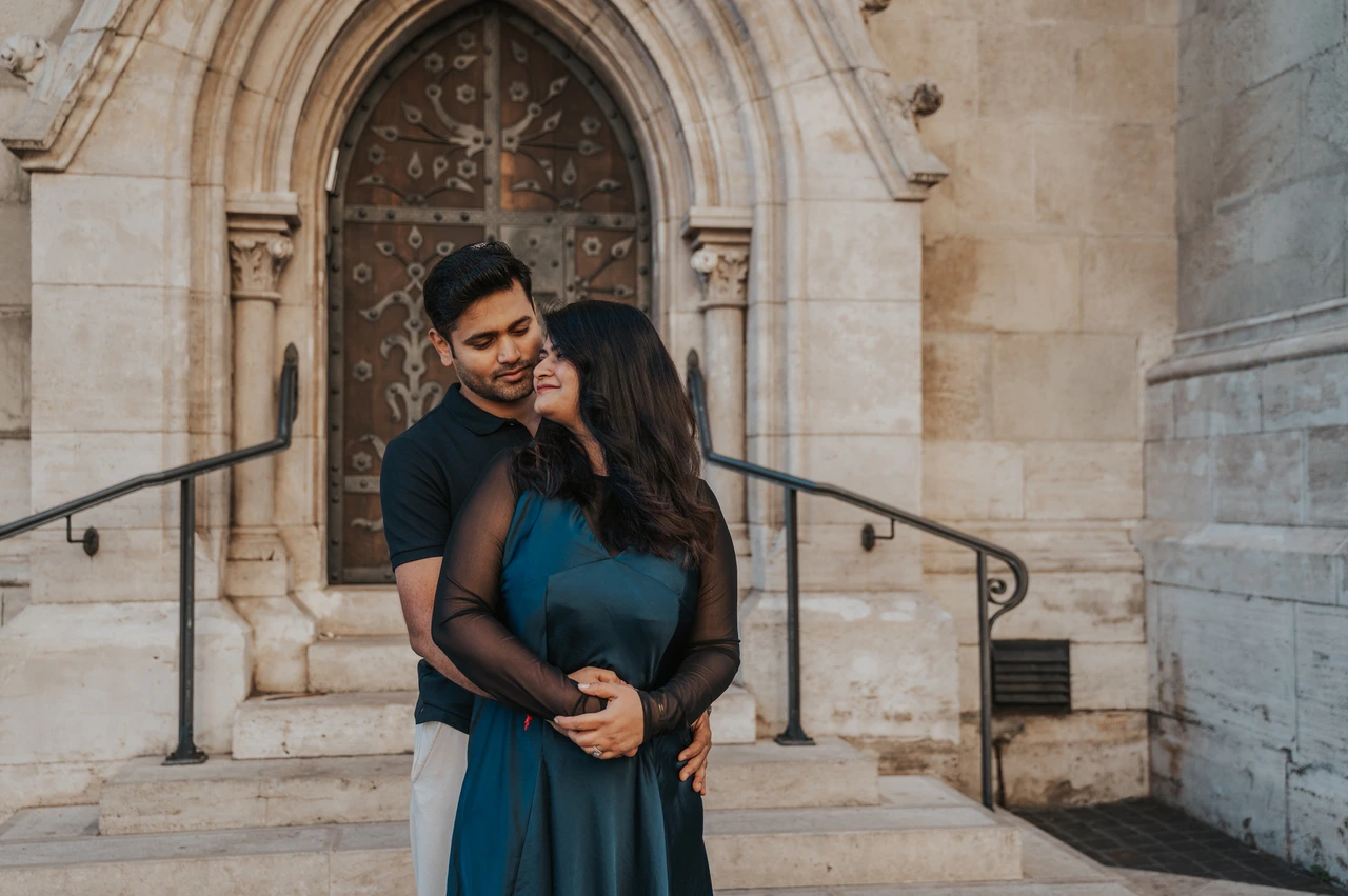 Budapest couple photoshoot: an embrace beneath the pointed church doorway A landscape portrait of the couple embracing beneath the pointed doorway of Matthias Church during a couple photoshoot in Budapest.