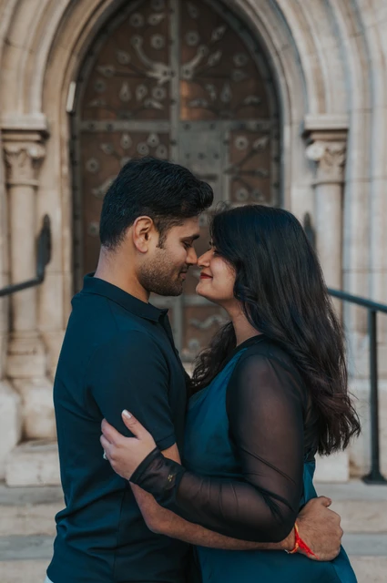Budapest couple photoshoot: a forehead kiss by the carved church door The man kissing his partner’s forehead beside the carved doorway at Matthias Church during a couple photoshoot in Budapest.