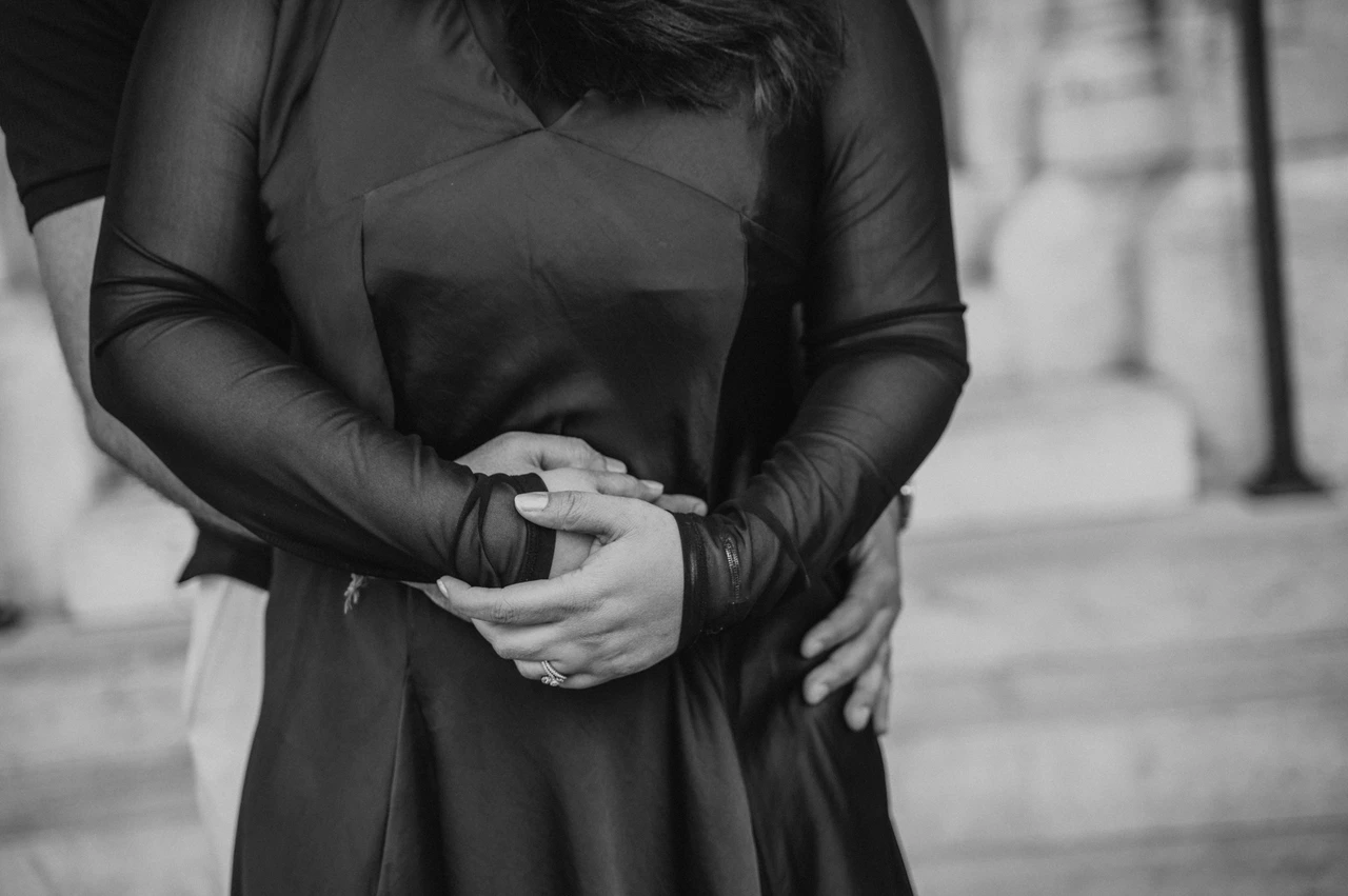 Budapest couple photoshoot: a detail of their hands beside the church in black and white Black-and-white photograph of a close detail of the couple’s joined hands against the woman’s dress beside Matthias Church during a couple photoshoot in Budapest.
